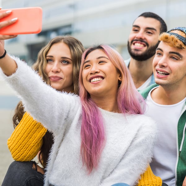 A group of young adults all smiling for a selfie